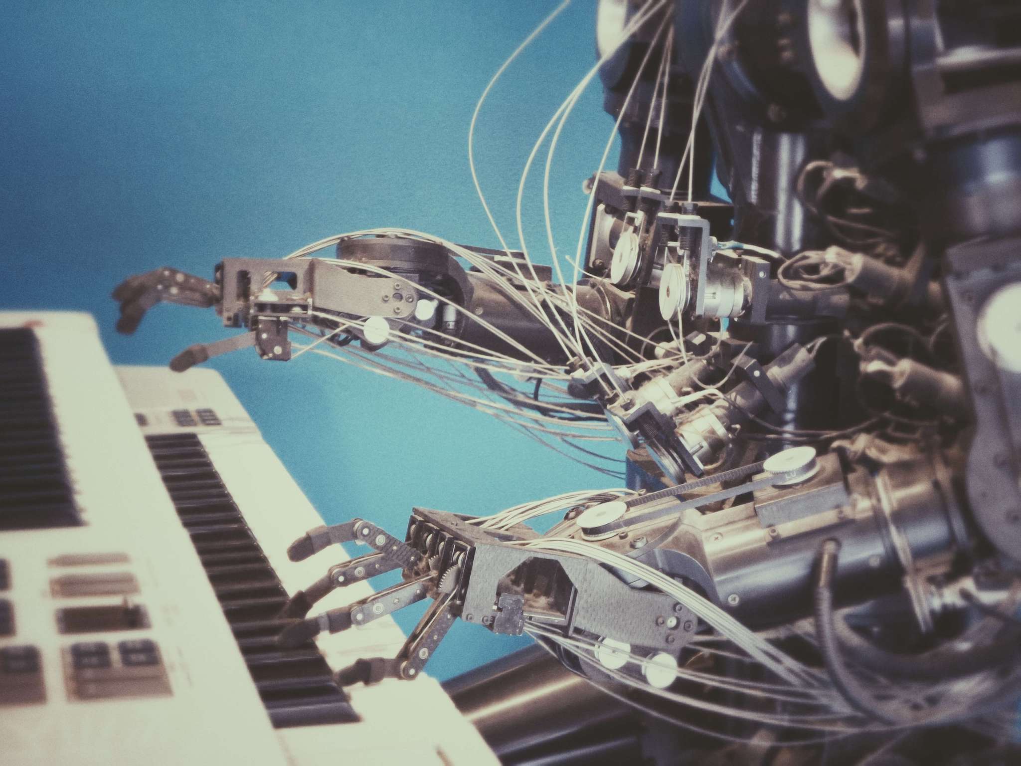 A robot sitting at a keyboard and playing it